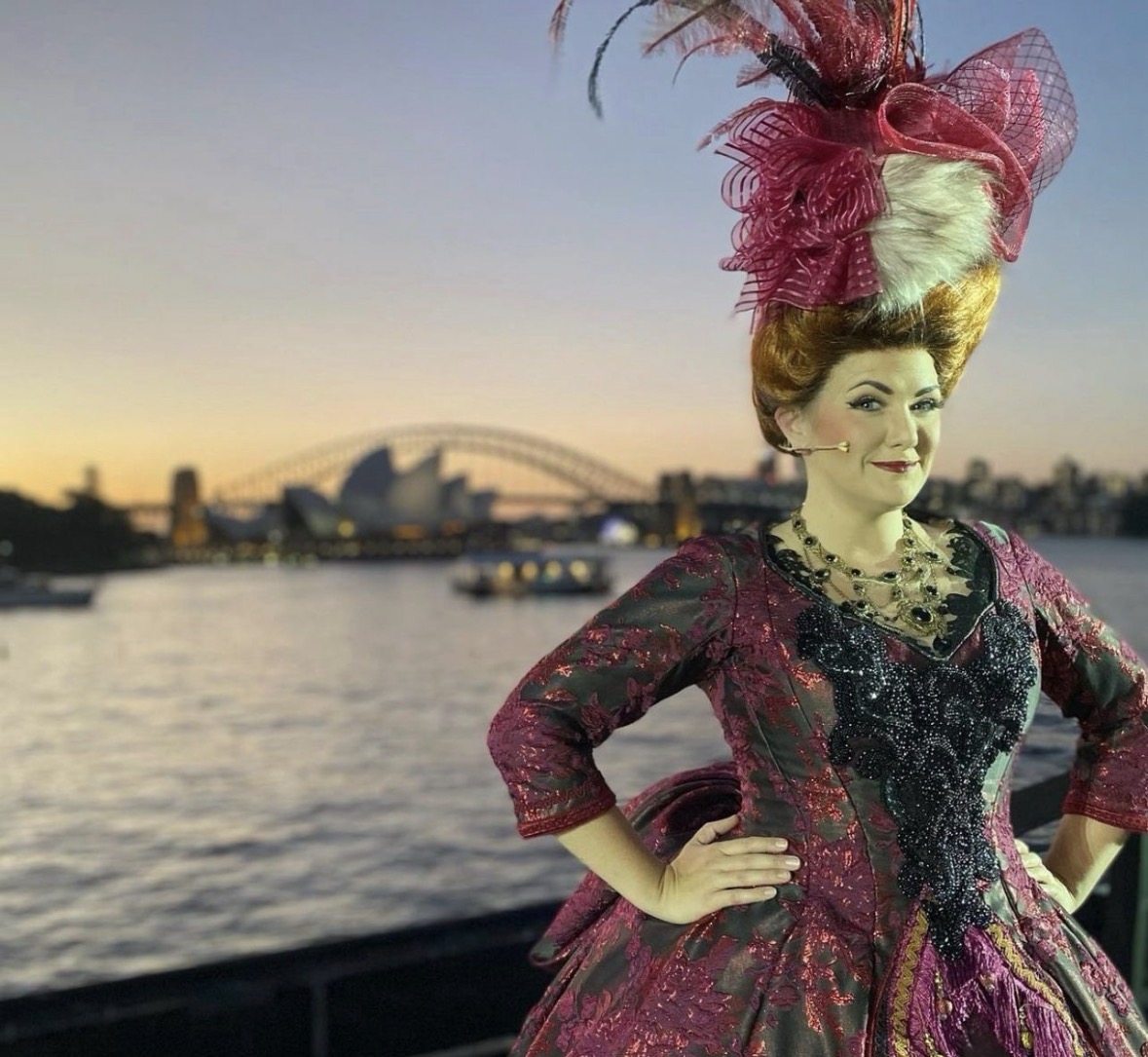 Period character in crimson gown and fascinator at Sydney Harbour
