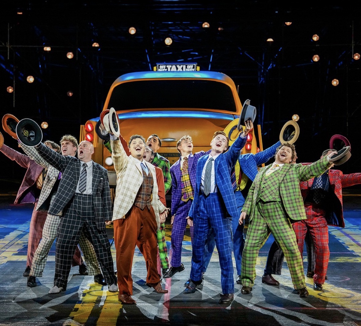 Guys and Dolls — ensemble of suited men cheering by a taxi