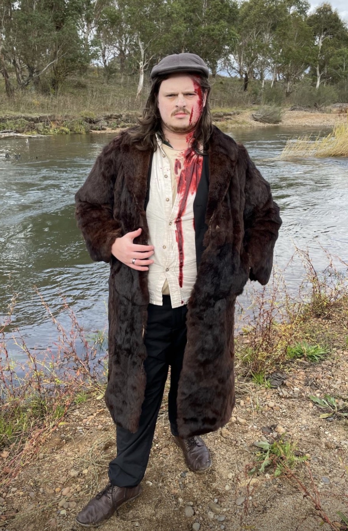 Period film character — fur coat with blood detail by the river
