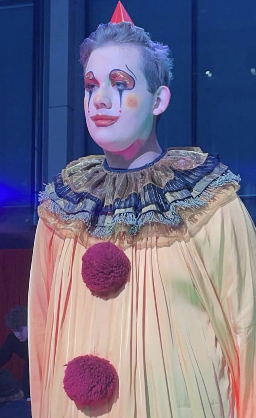 Pierrot clown with glittered eyes and ruffled collar on stage