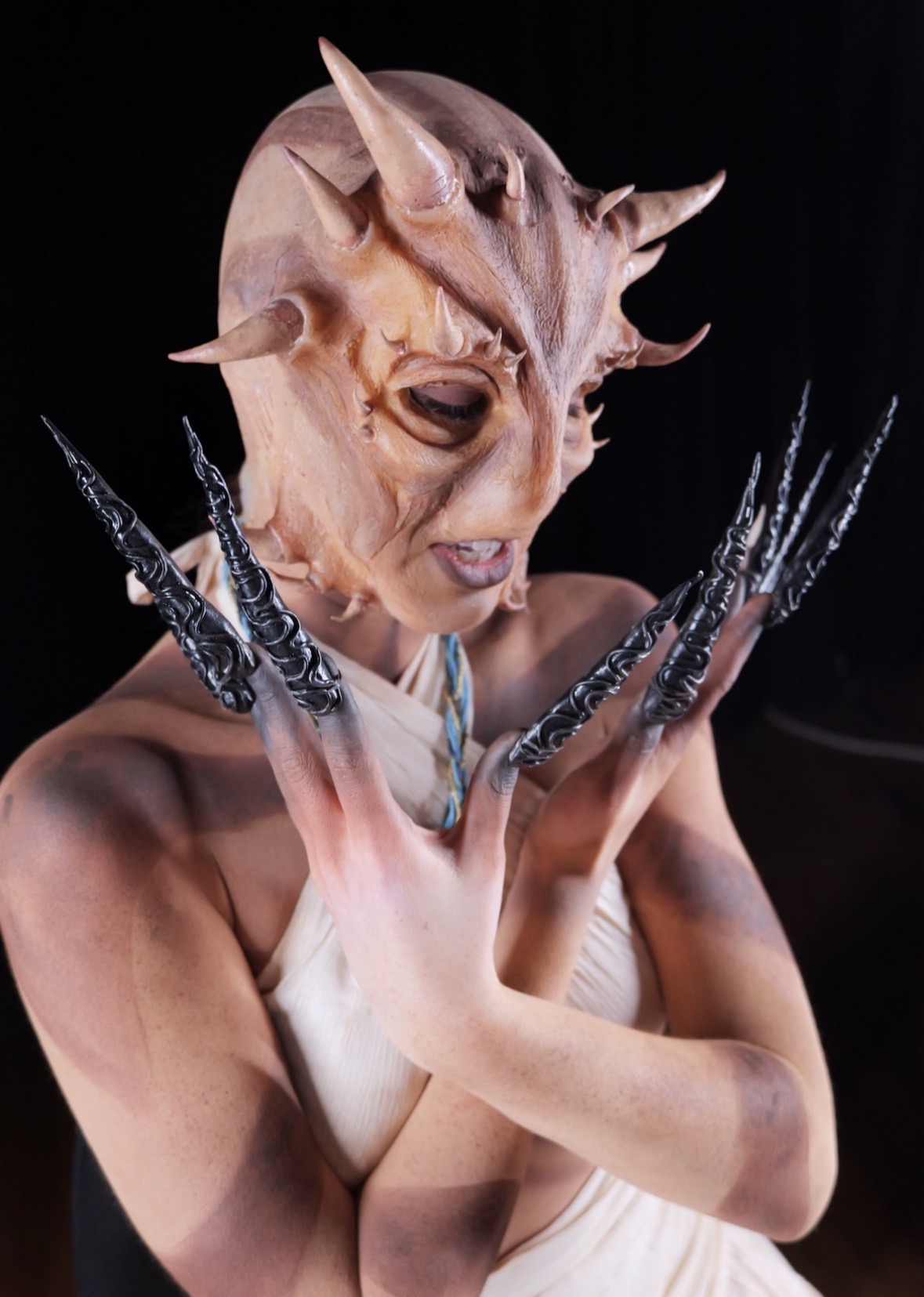 Horned creature prosthetic with sculpted silver claws