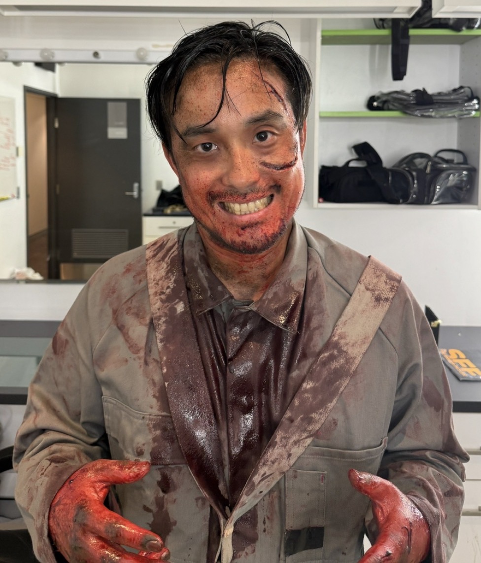 Blood-soaked survivor — face spatter and gore-soaked hands in coveralls